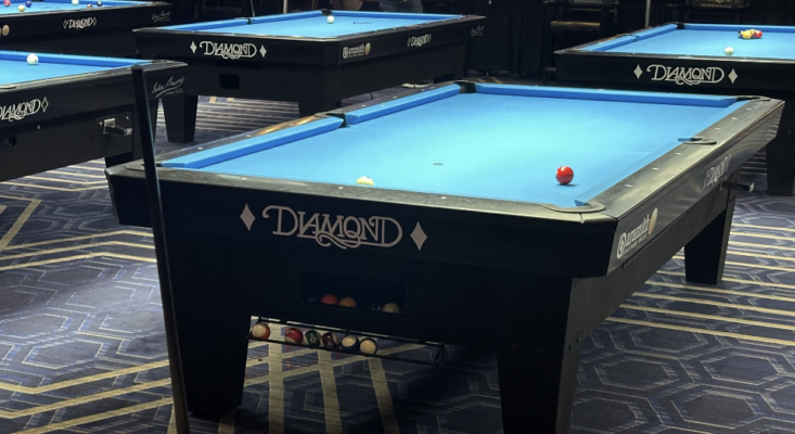 Diamond Table | Manar, Inc. | Manar, Inc. Wood to Plastic conversion Row of Diamond-brand pool tables with blue cloth in a game room; foreground table shows a few balls, including a red ball near a pocket.